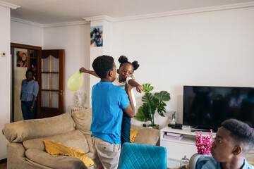Boy holding his little sister in his arms at home
