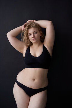 Overweight lady in lingerie touching hair in studio