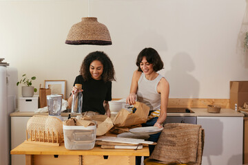 Happy diverse women unpacking groceries in kitchen