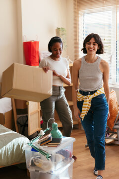 Cheerful flatmates unpacking boxes in new room