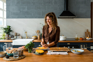 smiling senior woman cutting  fresh pumpkin