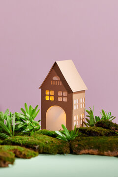 Mini house on small island with illuminated windows on beige backgroun