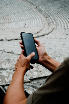 man using his smartphone in the Ancient Theatre of Epidaurus