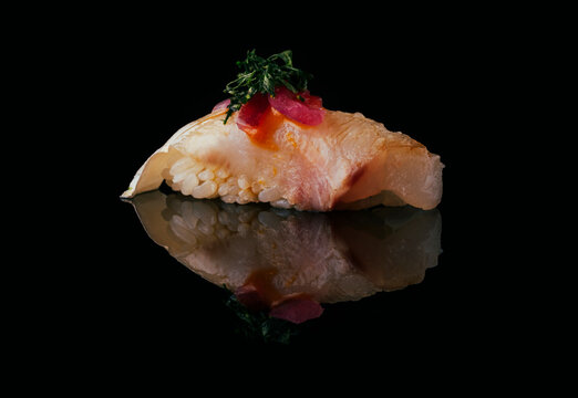 Delicious nigiri of sea bass over black background