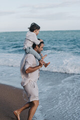 Naklejka premium Little Boy On His Dad's Shoulders. Family Having Fun Near Ocean 