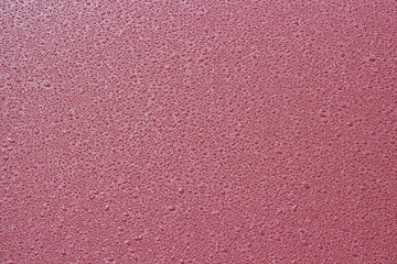 Raindrops on the surface of a sheet of metal,small drops of rain on a red sheet of metal