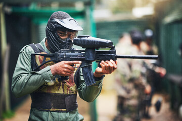 Fototapeta premium Paintball gun and black man player portrait with safety uniform for outdoor shooting game. Competitive tournament guy with helmet and camouflage vest ready for shooter sport and activity.