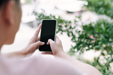 Male hand holding mock-up smartphone while standing at balcony 