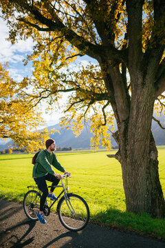 Man riding bike near beautiful tree with fall foliage
