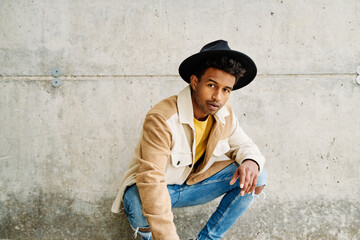 Stylish man posing against a concrete wall.