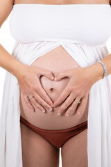 Fototapeta na wymiar Pregnant woman hands fingers sign heart belly in shirt in white background holding tummy