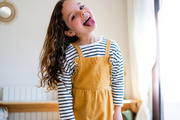 Funny girl with tongue out looking at camera from home