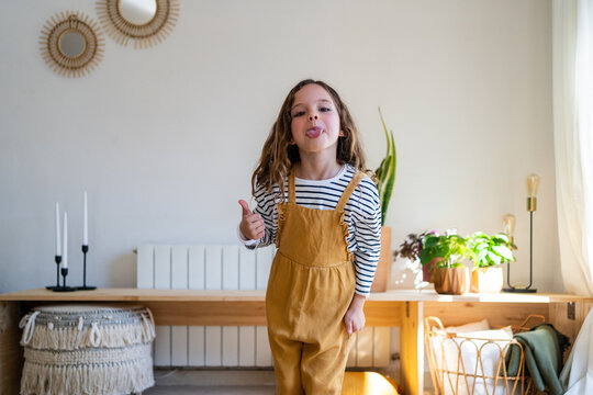 Portrait of happy girl with tongue out at home