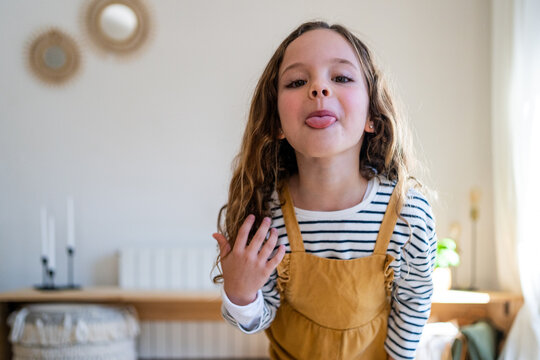 Funny girl with tongue out looking at camera from home