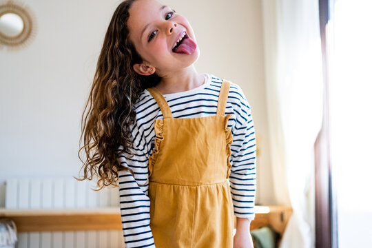 Funny girl with tongue out looking at camera from home