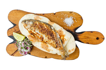 Whole fish baked with spices served on a wooden board with lemon and onion. Appetizing traditional mediterranean dish. Top view. Close-up. Isolated on white background.