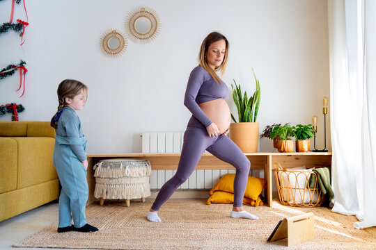 Prenatal mom exercising watching tablet at home