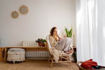 Relaxed woman on chair using smart phone from home