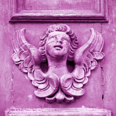 Sculpture of an old wooden angel against a wooden door of a church - more than 100 years old