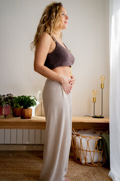 Pensive woman touching her belly at home