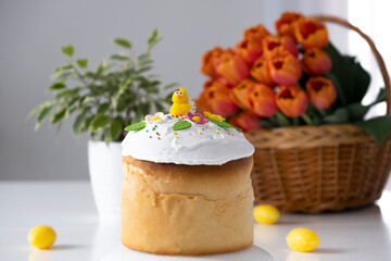 Traditional Easter cake with marshmallow glaze and spring decoration, orange tulips on background. Happy Easter. Recipe of Easter bakery. Festive pastry for spring holidays.