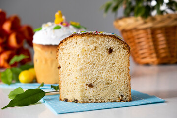 Easter panettone with marshmallow glaze and spring decoration, orange tulips on background. Happy Easter. Recipe of Easter bakery. Festive pastry for spring holidays.