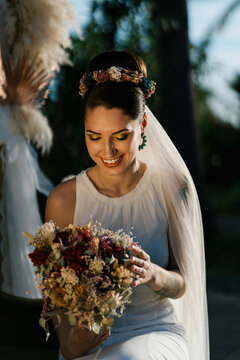 Cheerful bride admiring bouquet during wedding