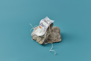 Trendy composition of dollar tied to stones.