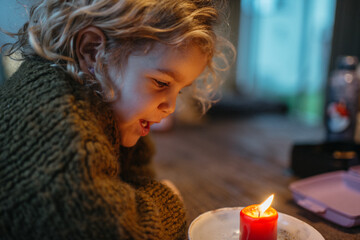 Kid looking at red candle burning