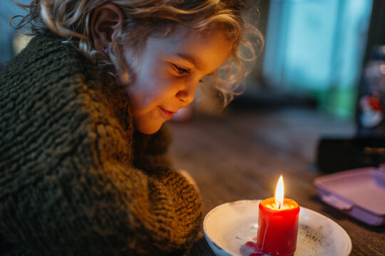 Kid looking at red candle burning