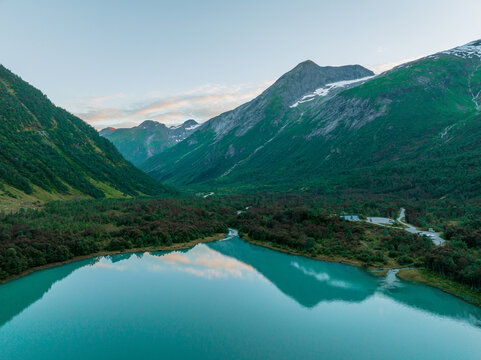 Aerial view of turquoise lake surrounded by forest in Norway 