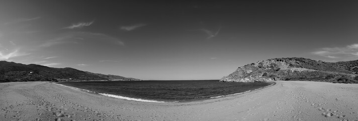 Panoramic view of the amazing golden sandy beach with turquoise waters at Kalamos in Ios in black and white