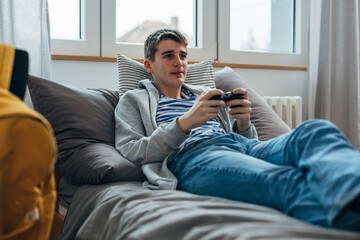 Fototapeta premium Teenage boy with pimples plays a game at home