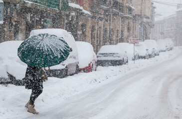 Nieve en el casco urbano de una ciudad con gente espalando, paseando, con paraguas
