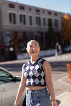 Stylish woman with shaved head working in city setting 