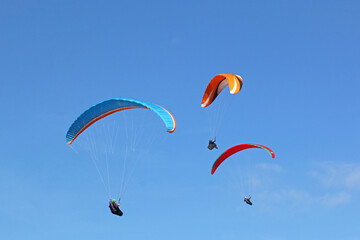 Paragliders flying in a blue sky	
