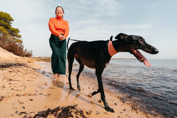 Woman walking her black greyhound dog