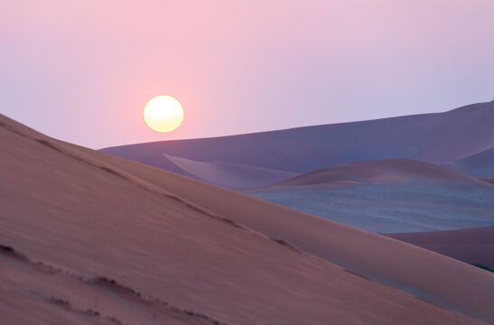 Sand dunes in front of the sun at sunset in Namibia, Africa.