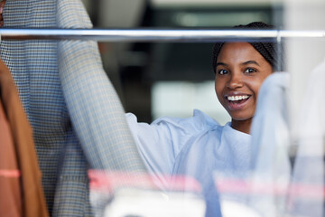 Shopping, clothes and face of black woman in store with choice on rack for sale, discount and...