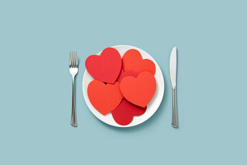 Lots of red paper hearts on white plate.