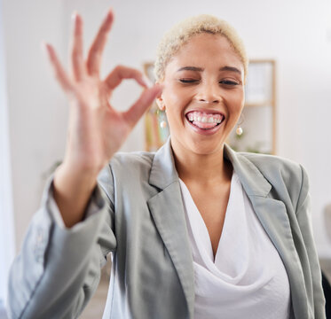Portrait, tongue and emoji with a business black woman winking in her office at work to gesture a perfect hand sign. Face, motivation and succes with a female employee feeling happy or proud
