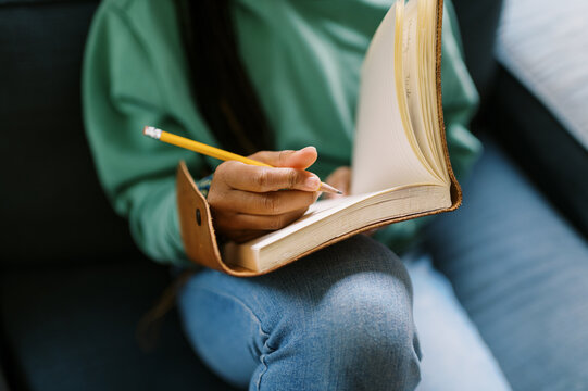 black teenage girl sitting down writing in a journal