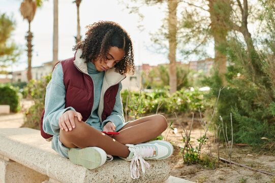 Teen girl texting on a park bench