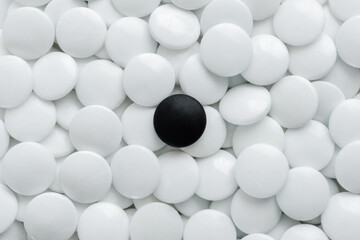 One black Go stones and many white Go stones.