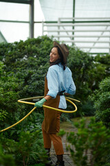 Young woman gardener having fun with watering hose