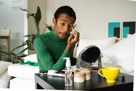 Queer MAN applying make up at home