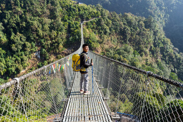 Man hiking on suspended bridge in Nepal