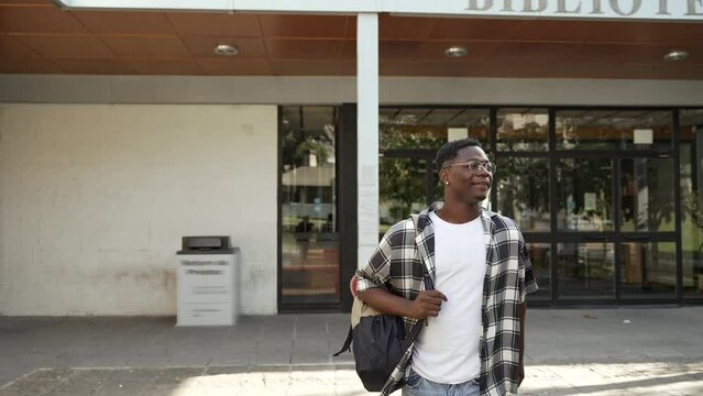 Happy African student walking out of University building - Success after exams