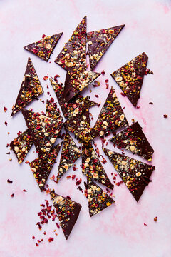 Pieces of Rose, Hazelnut and Pistachio Chocolate Bark on Pink Surface