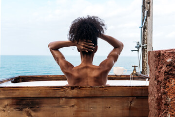 Black woman relaxing in bathtub against sea